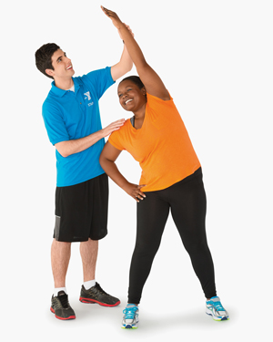 trainer helps woman stretch